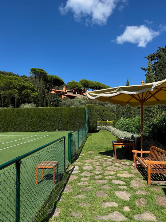 Italian villa garden grass court with yellow umbrella
