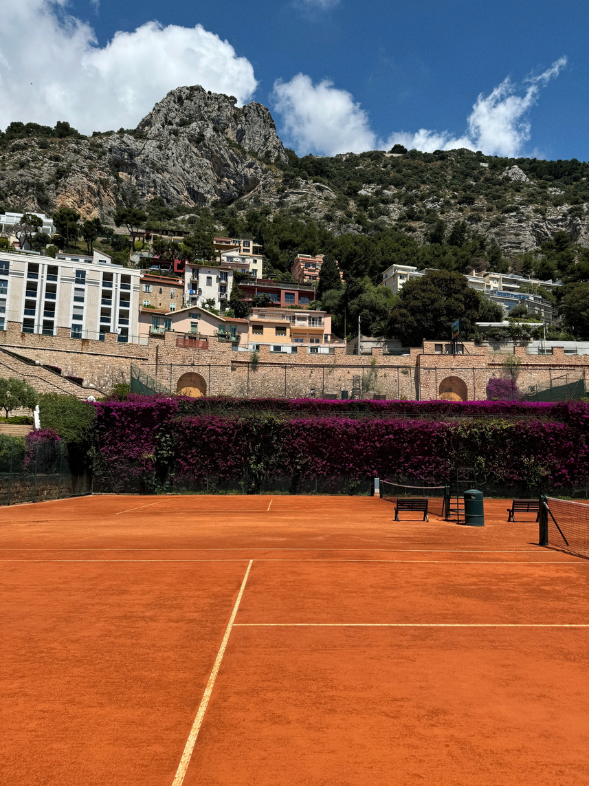 Clay court with bougainvillea and rocky mountain, Monaco
